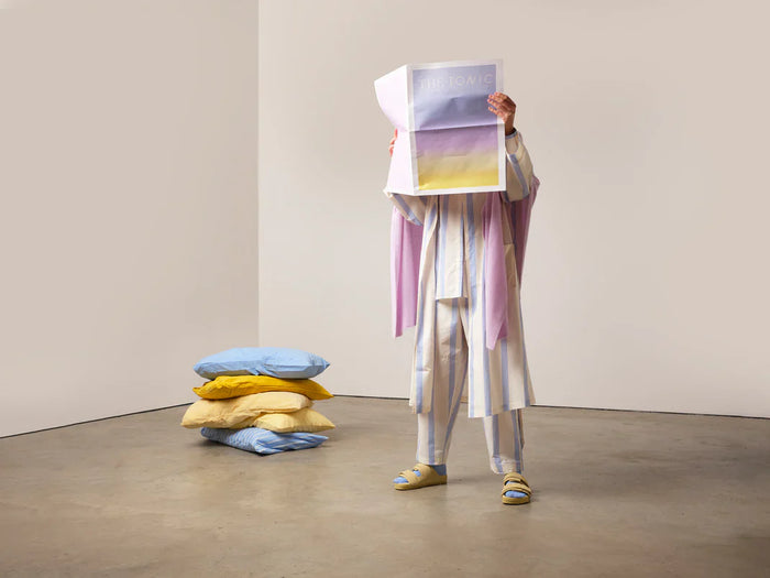 Person wearing Tonic London clothing with face covered by newspaper