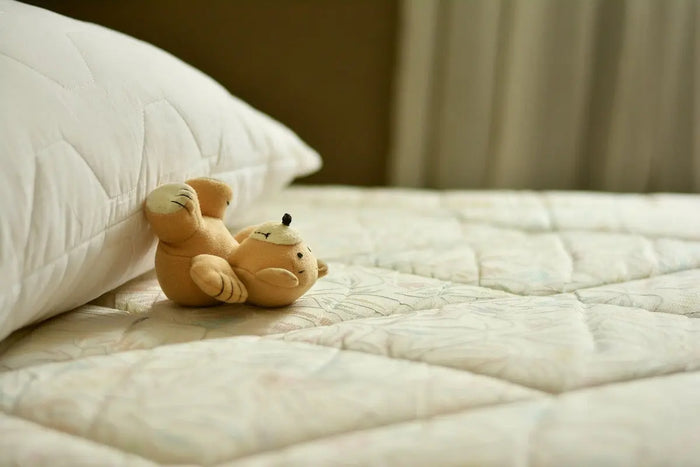 teddy bear lying on bare mattress