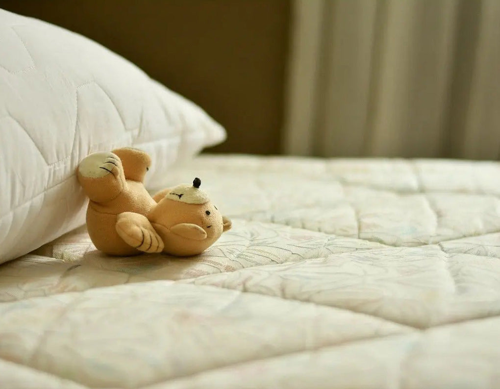 teddy bear lying on bare mattress