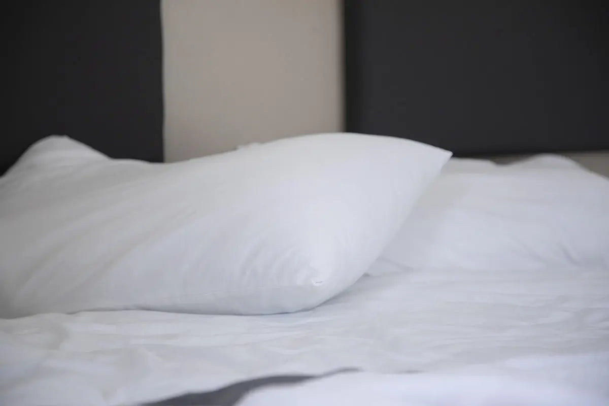bare pillow resting on bed