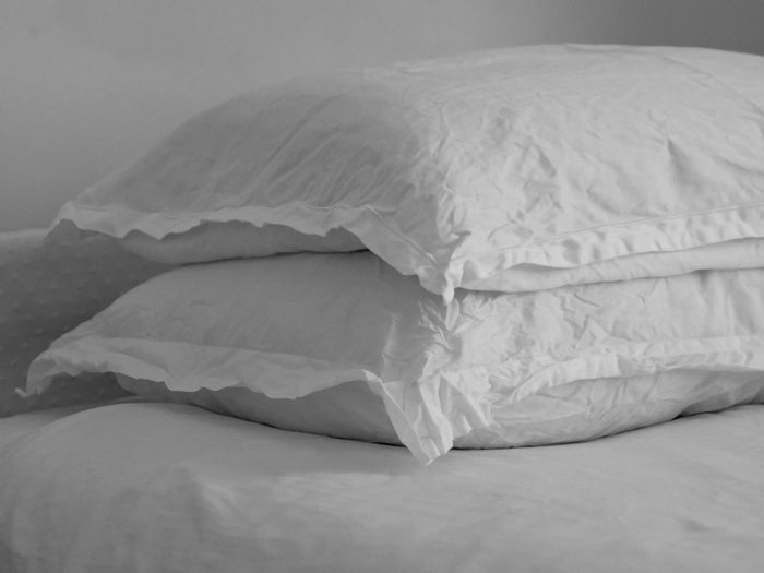 Two uncovered white pillows stacked on each other