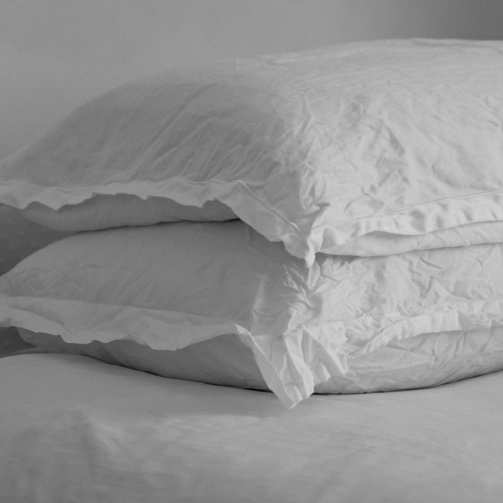 Two uncovered white pillows stacked on each other
